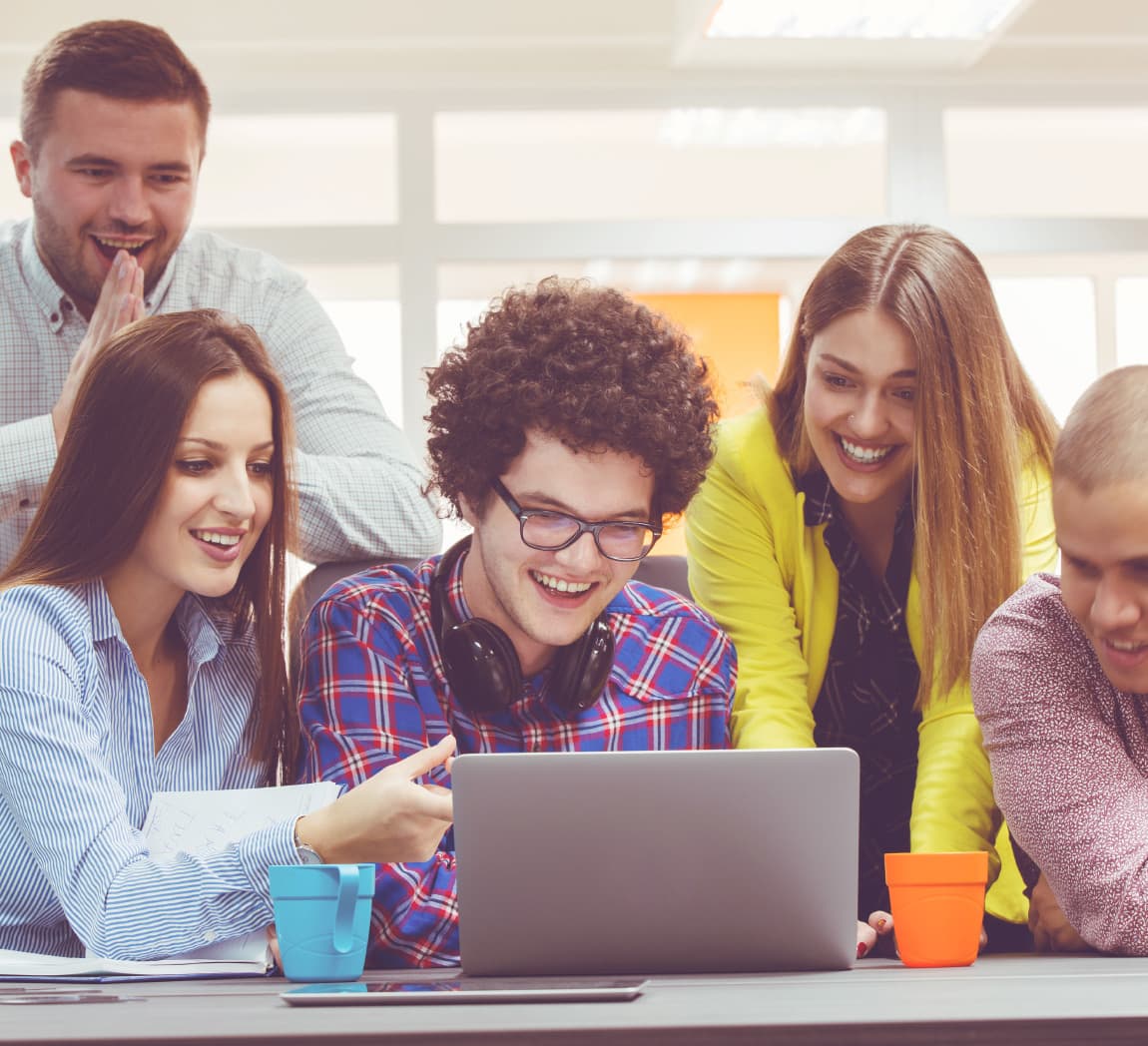 A group of young people around a laptop